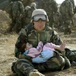 Marzo 2003: un marine americano tiene in braccio un bambino iracheno in una zona centrale del Paese dopo uno scontro a fuoco che ha coinvolto dei civili (Damir Sagolj/Reuters)