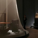 Sala iniziale con contrapposizione tra la piattaforma con fondale metallica per i mobili classici e la campana in garza scenica per i mobili moderni