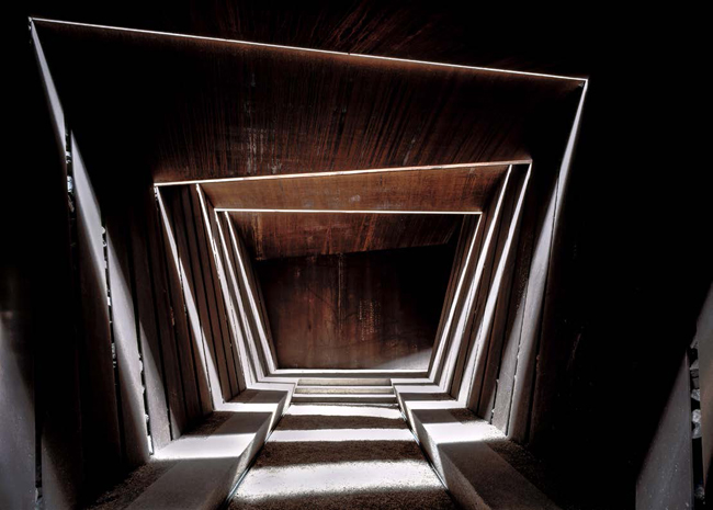 Veduta dell'interno della cantina verso la sala di degustazione. Le fenditure tra le lastreconsentono all'aria, alla luce e alla pioggia di entrare e creare ombre mutevoli 