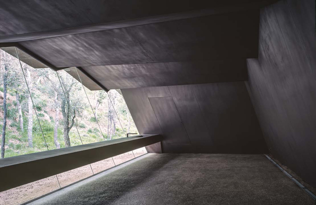 Veduta dell'interno della cantina verso la sala di degustazione. Le fenditure tra le lastreconsentono all'aria, alla luce e alla pioggia di entrare e creare ombre mutevoli 