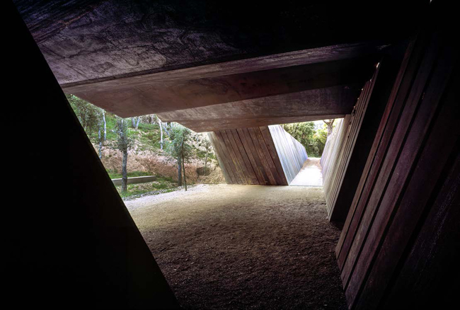 Veduta dell'interno della cantina verso la sala di degustazione. Le fenditure tra le lastreconsentono all'aria, alla luce e alla pioggia di entrare e creare ombre mutevoli 